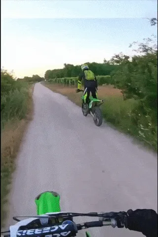 A sequence of six images shows a motorcyclist riding a green dirt bike on a rural dirt road lined with vineyards. In the…