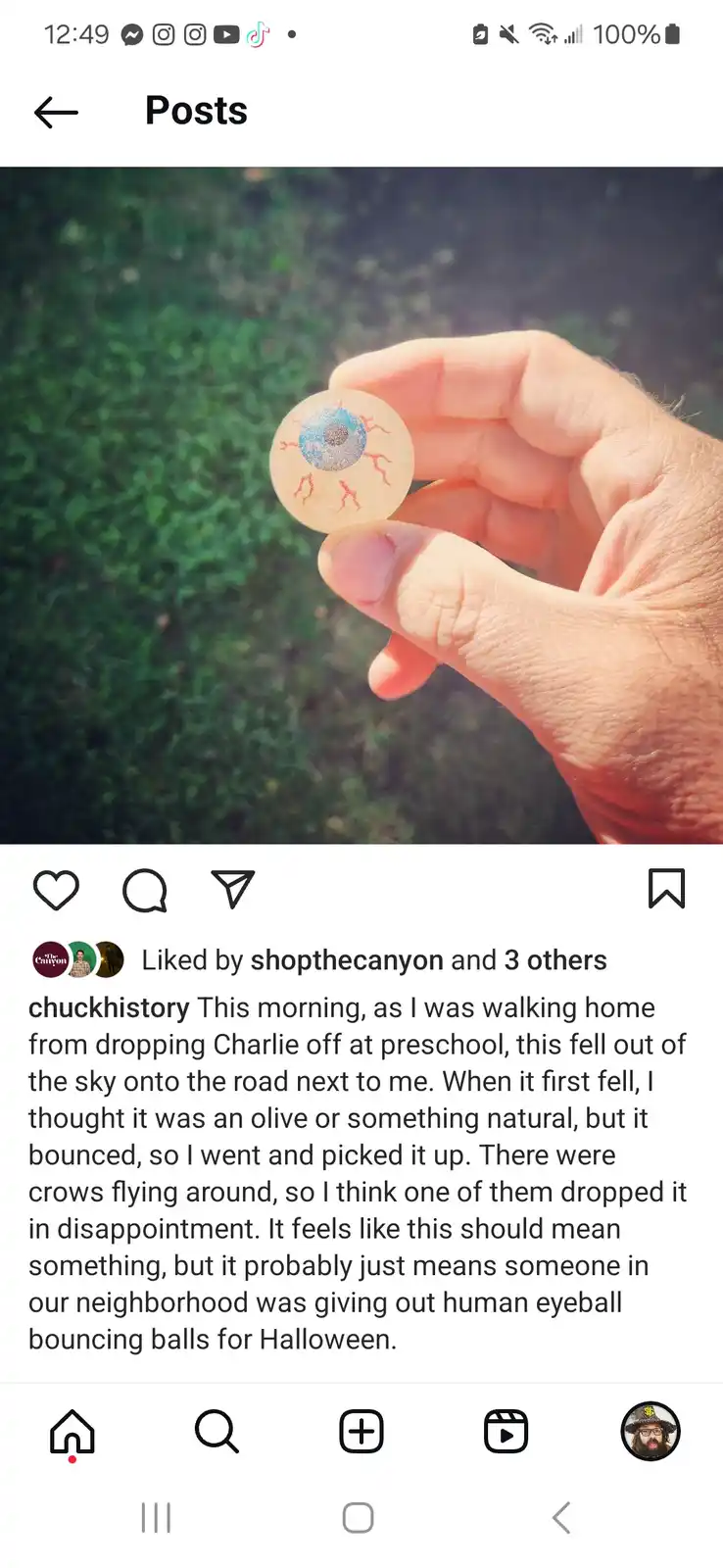 A hand holds a small, round, translucent object resembling a human eyeball with a blue iris and red blood vessels, against a…