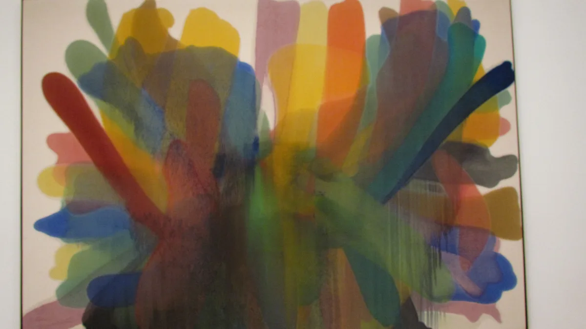An abstract painting featuring overlapping, translucent, colorful brushstrokes radiating outward from a central point…