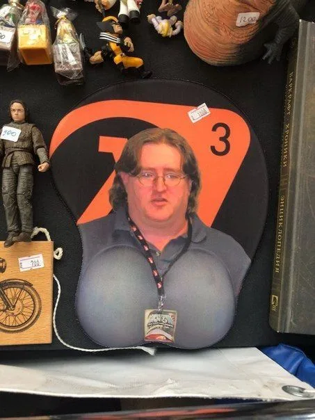 A photo shows a large, orange and black mousepad featuring a photo of Gordon Ramsay with exaggerated, cartoonishly large…