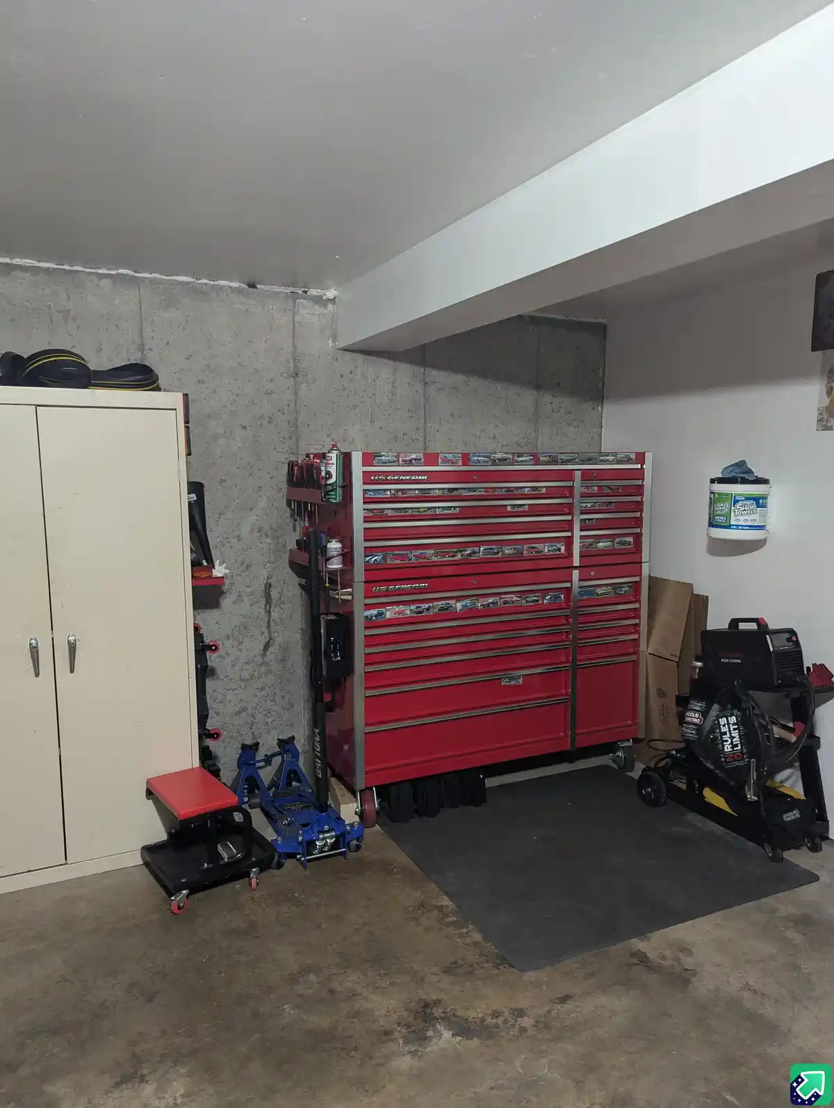 A well-organized garage features a large red U.S. General tool chest with car decals on its drawers, surrounded by…