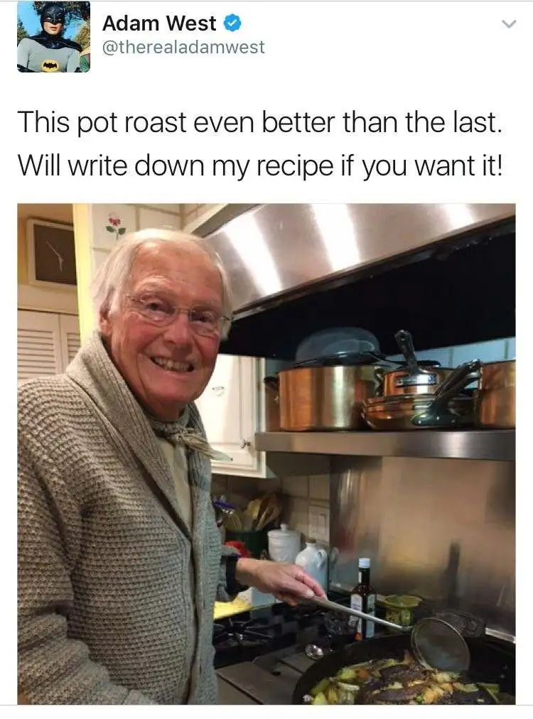 An elderly man with glasses and a beige sweater smiles proudly while stirring a pot of food on a stove in a kitchen. Above…