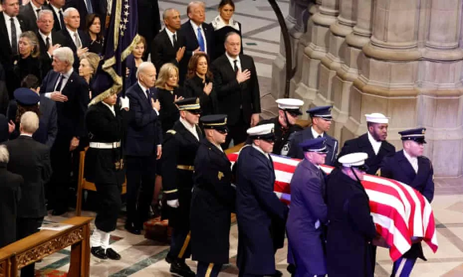 A solemn funeral procession inside a grand cathedral, with U.S. military personnel carrying a casket draped in an American…