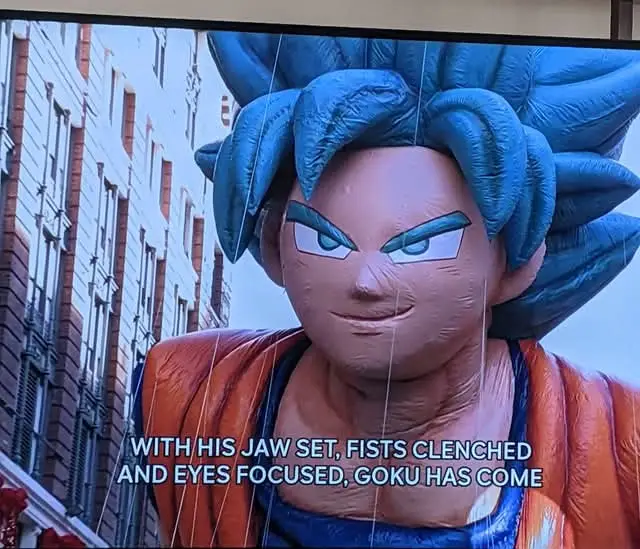 A large, inflatable statue of the anime character Goku from Dragon Ball, shown with his signature spiky blue hair, intense…