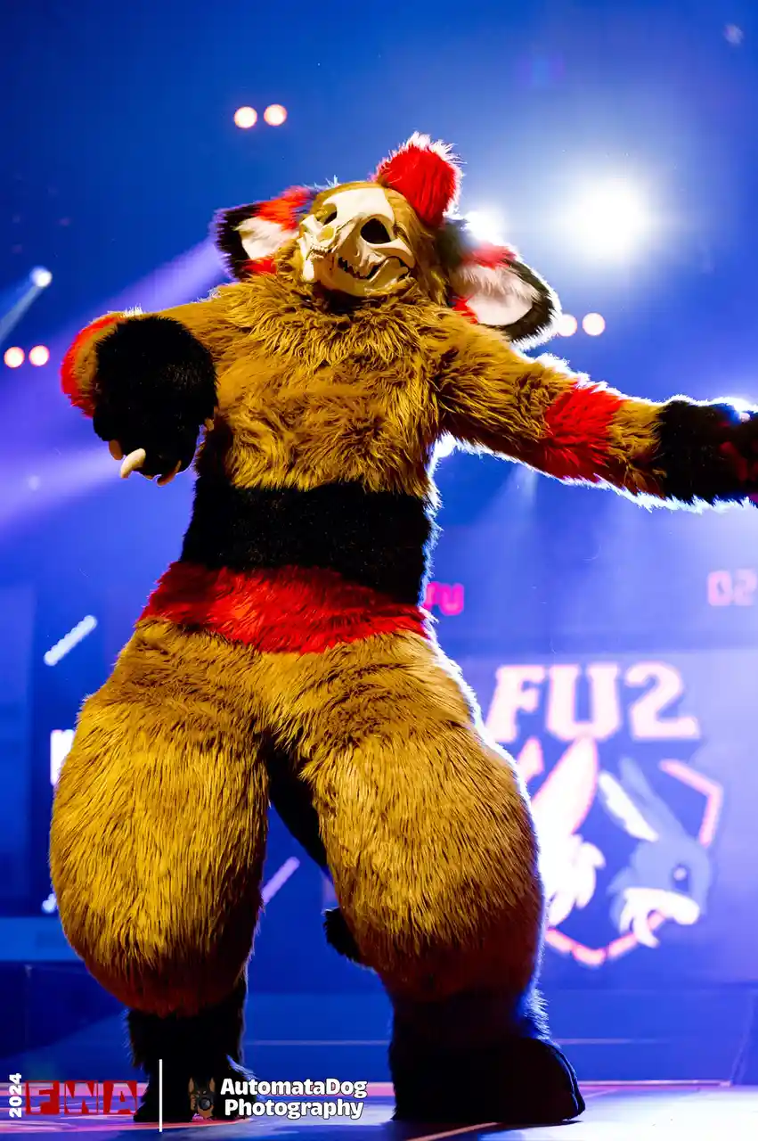 A person in a full-body furry costume resembling a skeletal, anthropomorphic animal with brown fur, red and black accents…