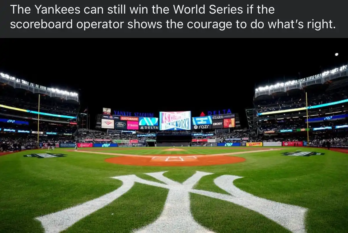 A wide-angle night photo of Yankee Stadium, showing the iconic white 'NY' logo painted on the green grass in the foreground…