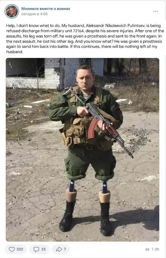 A man in military fatigues stands outdoors holding an assault rifle, visibly wearing prosthetic legs with beige sockets and…