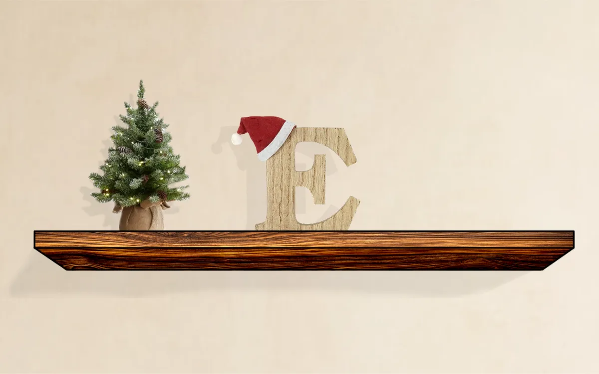 A wooden shelf holds a small decorated Christmas tree in a burlap sack and a large wooden letter 'E' wearing a red Santa…
