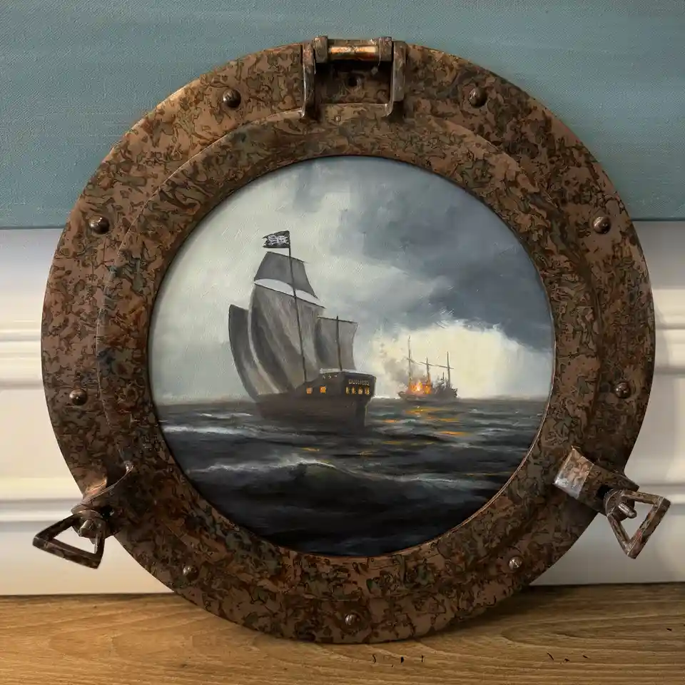 A circular, weathered brass porthole frame displays a painting of a pirate ship with a skull-and-crossbones flag sailing…