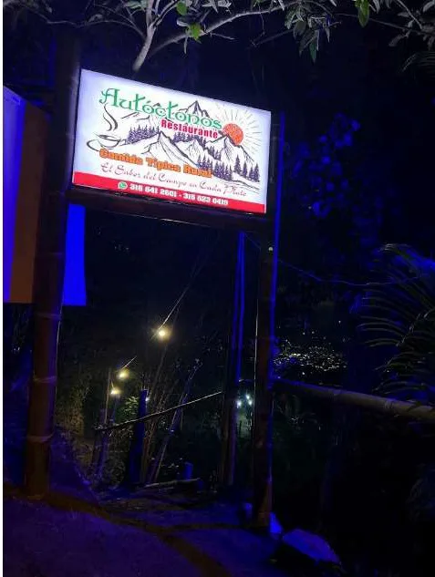 A brightly lit restaurant sign at night reads 'Autóctono Restaurante' with 'Cocina Tipica Huila' and 'El Sabor del Campo en…