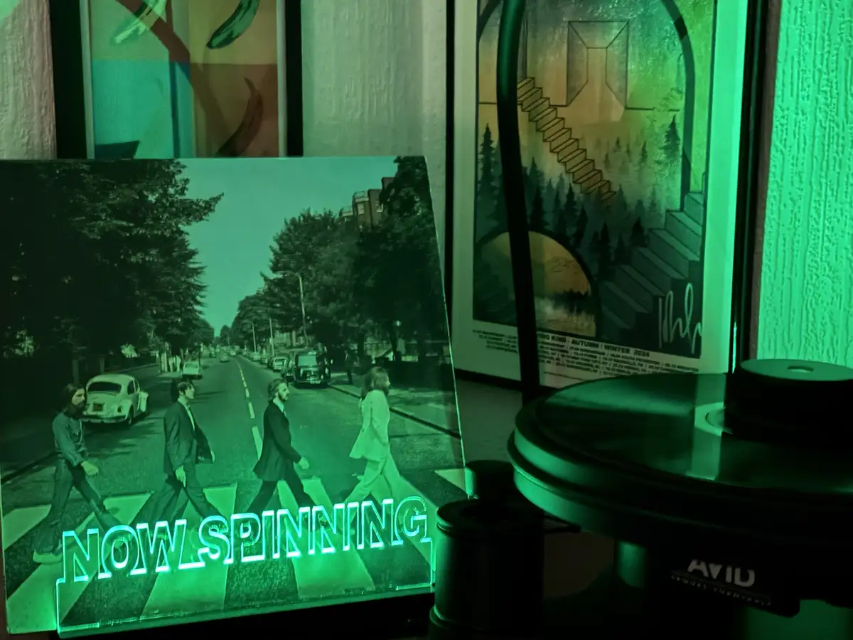 A green-tinted photo of The Beatles crossing a street is displayed next to a record player, with the glowing text 'NOW…