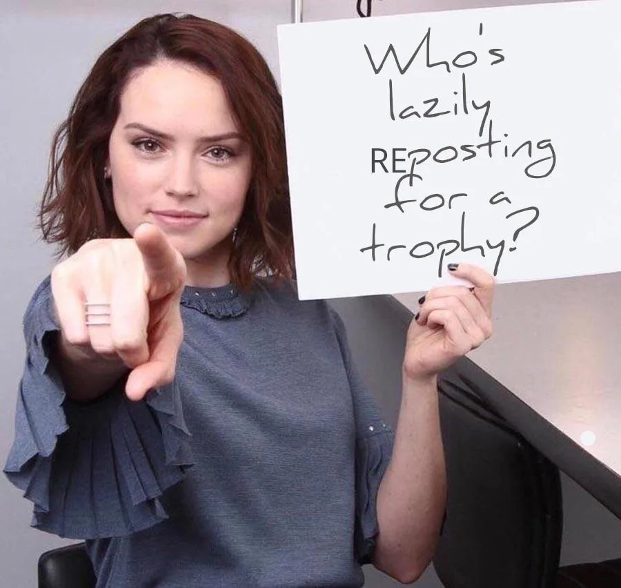 A woman with brown hair and a gray ruffled shirt points directly at the viewer while holding a white sign with handwritten…