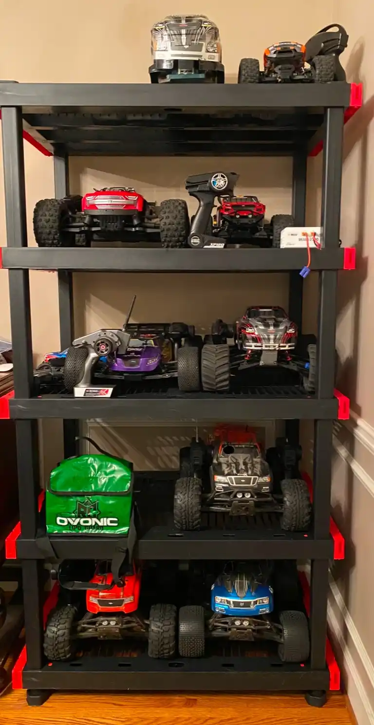 A black multi-tiered storage shelf filled with numerous remote-controlled cars and trucks of various colors and designs…
