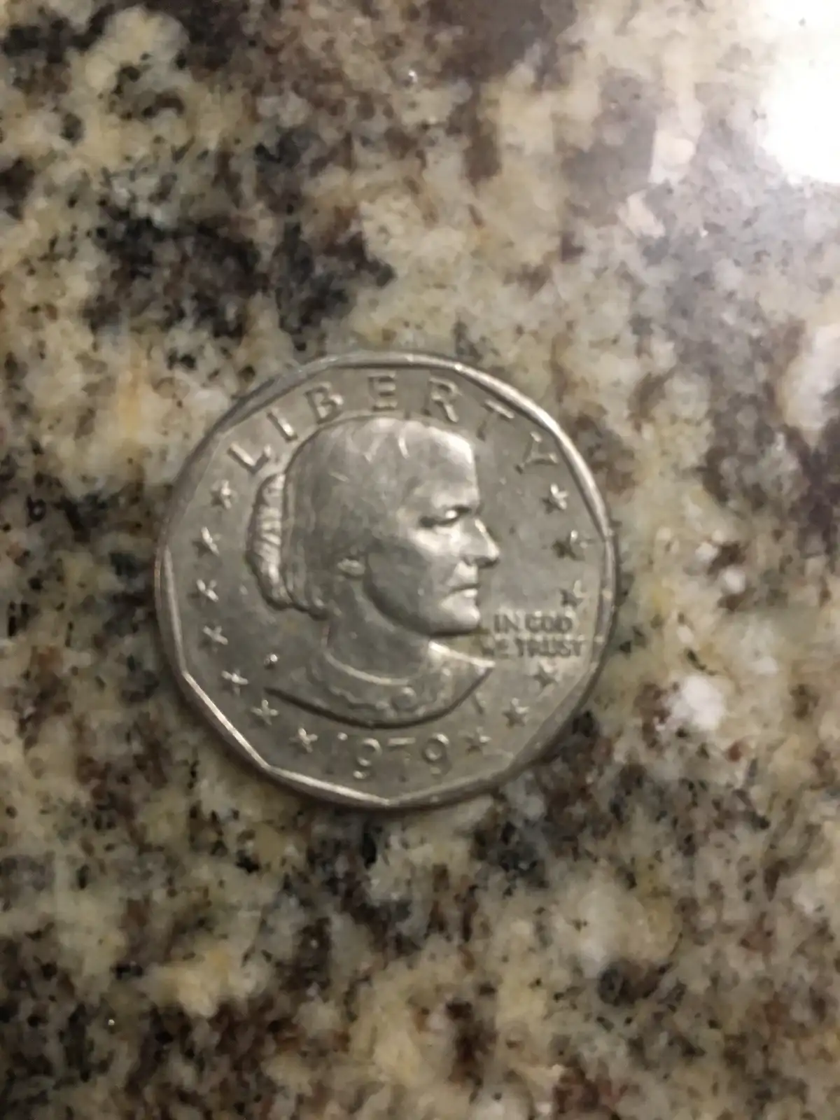 A close-up photo of a 1979 United States quarter featuring the profile of George Washington, resting on a speckled granite…