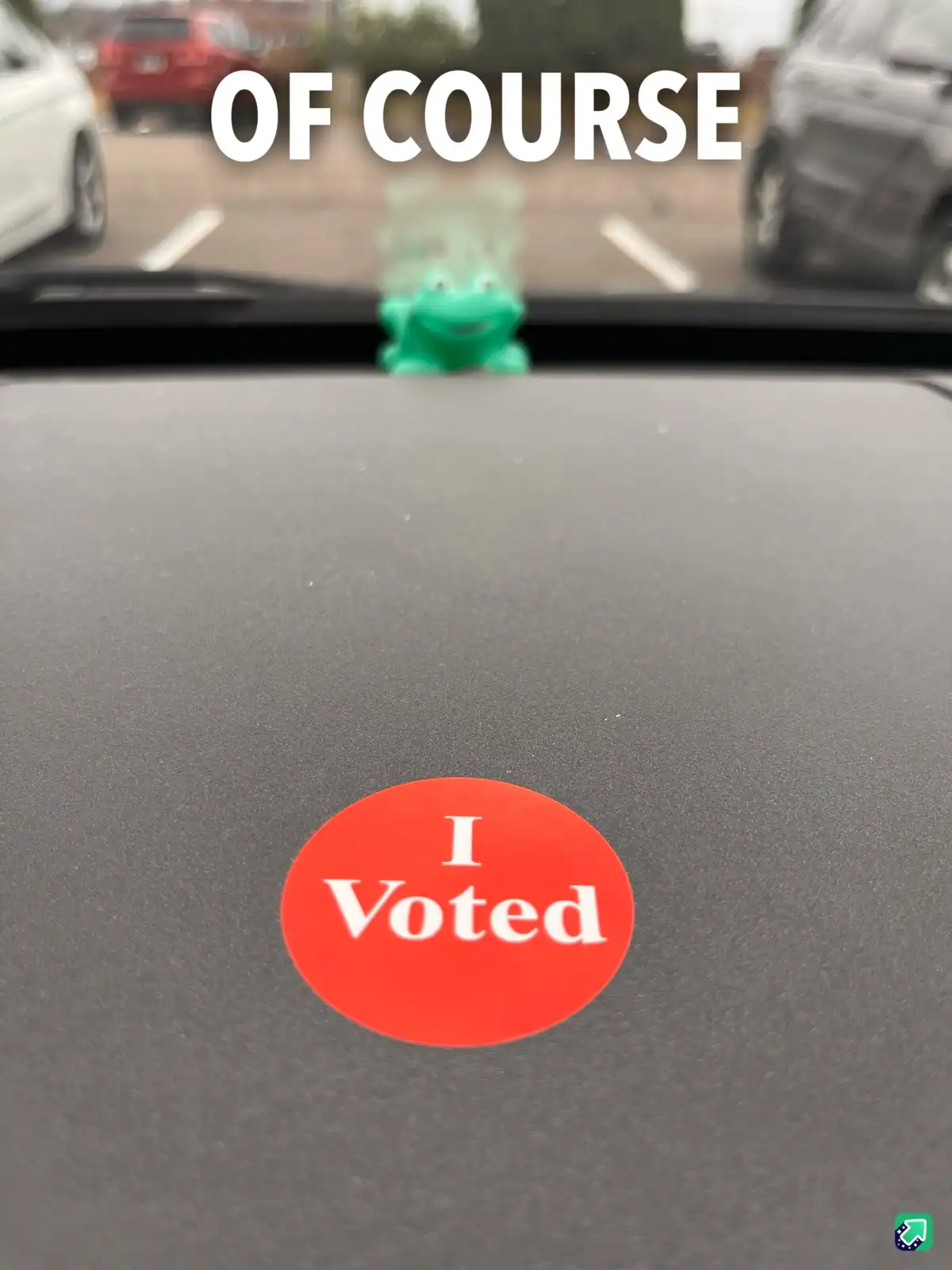 A close-up photo shows a red circular 'I Voted' sticker stuck to the dark gray dashboard of a car. In the blurred…
