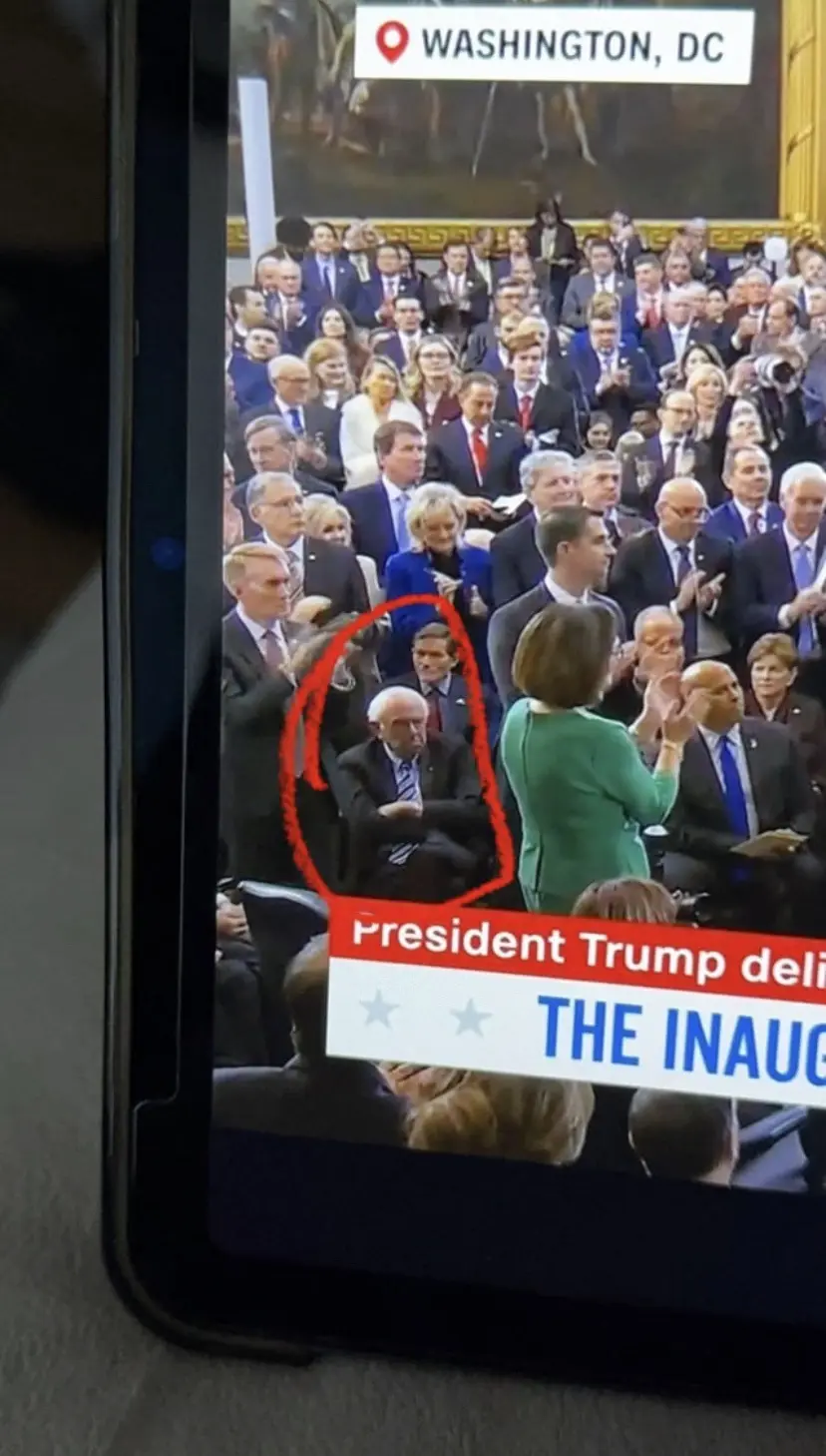 A tablet screen shows a live broadcast of an inauguration in Washington, DC, with a crowd of formally dressed people…