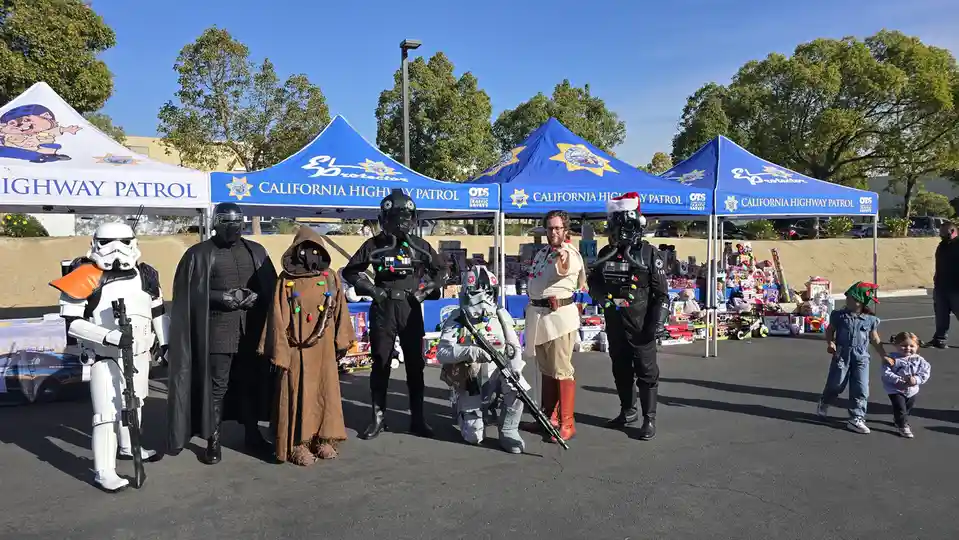 A group of people dressed as Star Wars characters, including Stormtroopers, Kylo Ren, and a Wookiee, stand in front of…
