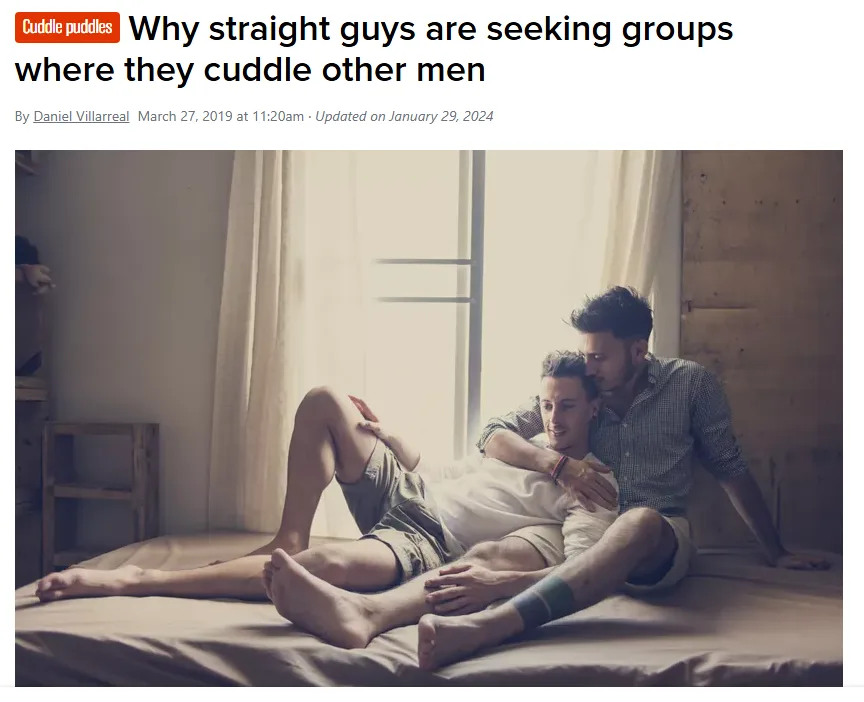 Two men are lying on a bed in a softly lit room, one with his arm wrapped around the other in a comforting embrace. The…