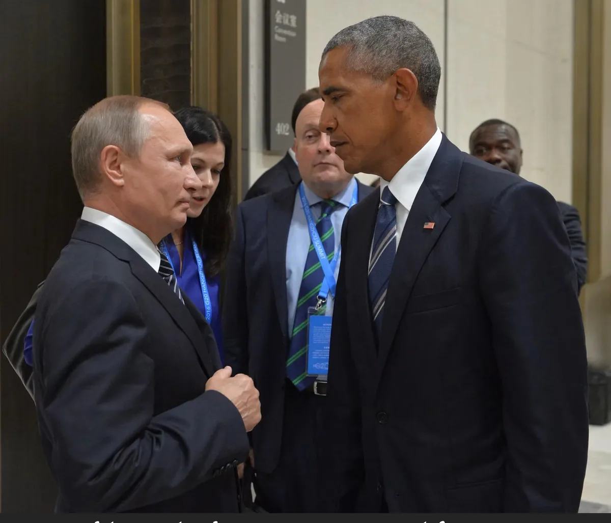 A photo of Barack Obama and Vladimir Putin standing face-to-face in a hallway, both looking intently at each other. Obama is…