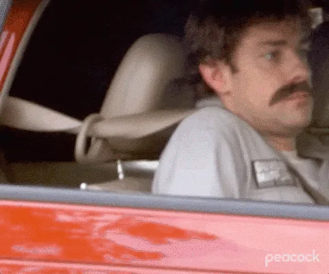 A six-panel image sequence shows a man with a mustache in a red car. In the first three panels, he looks around with a…