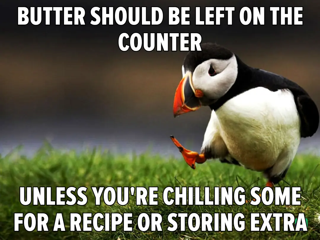 A close-up photograph of a puffin standing on green grass, looking slightly to the side with one foot lifted. The image has…