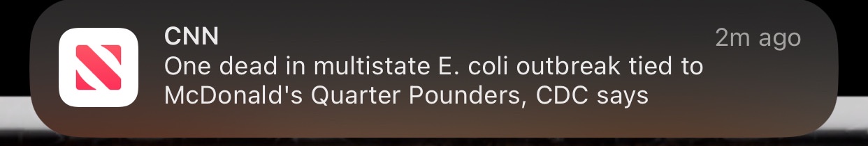 A screenshot of a CNN notification on a smartphone, showing a headline about a deadly E. coli outbreak linked to McDonald's…