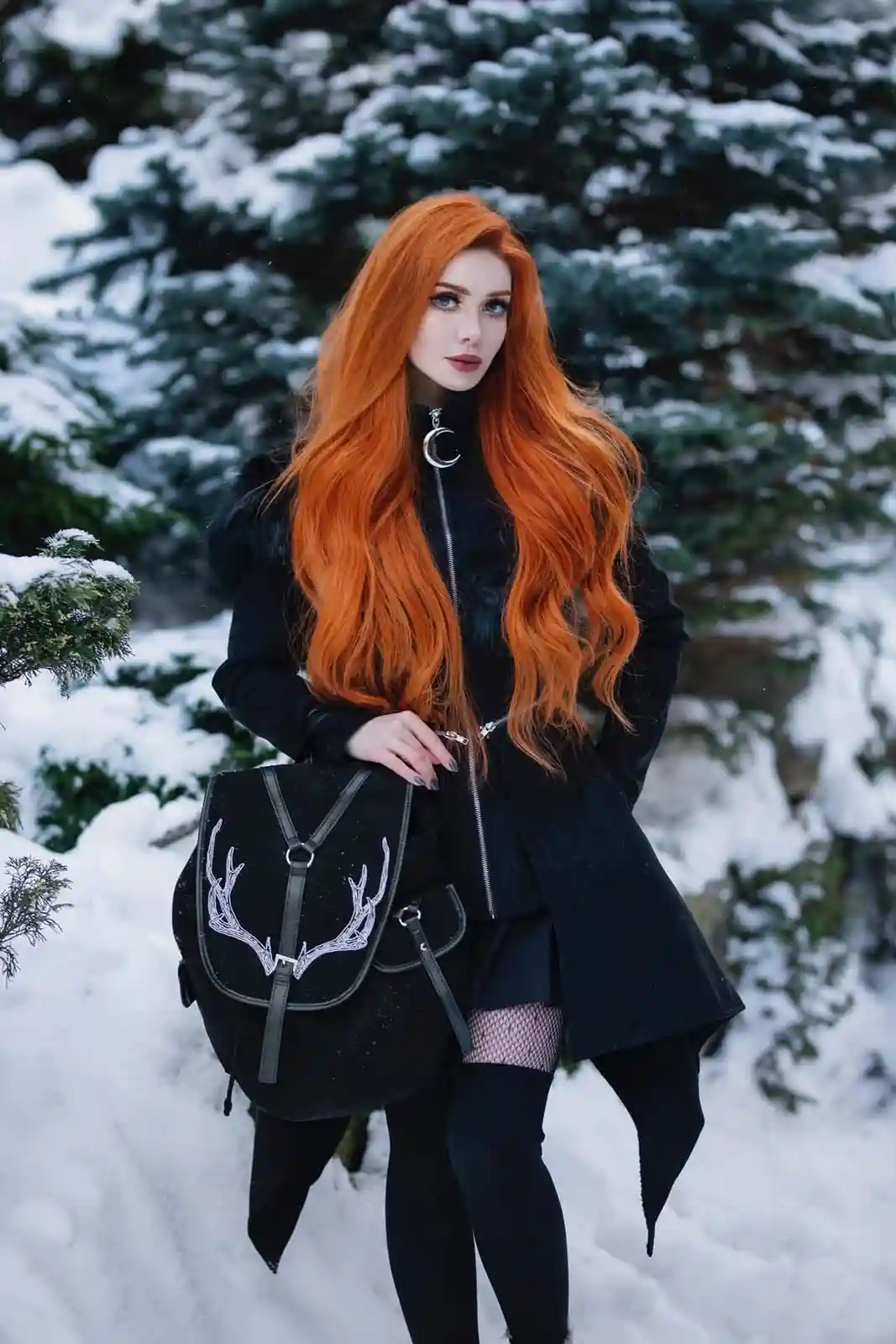 A woman with long, vibrant orange hair stands in a snowy forest, wearing a black coat with a moon-shaped zipper pull, black…