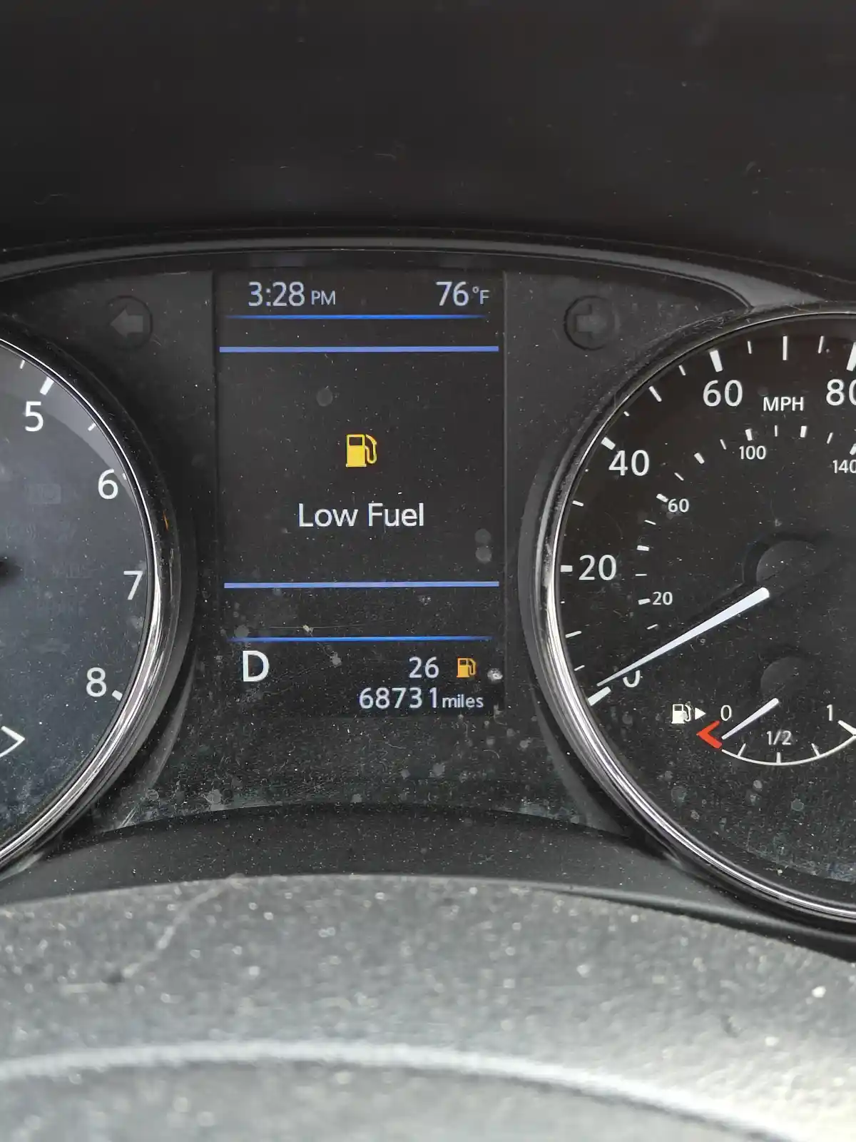 A close-up of a car's dashboard showing a digital display with a yellow fuel pump icon and the text 'Low Fuel' centered. The…