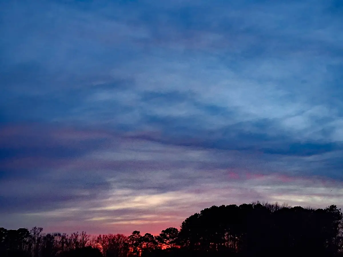 A serene twilight sky with soft blue and purple clouds streaking across the upper frame, transitioning to warm pink and…