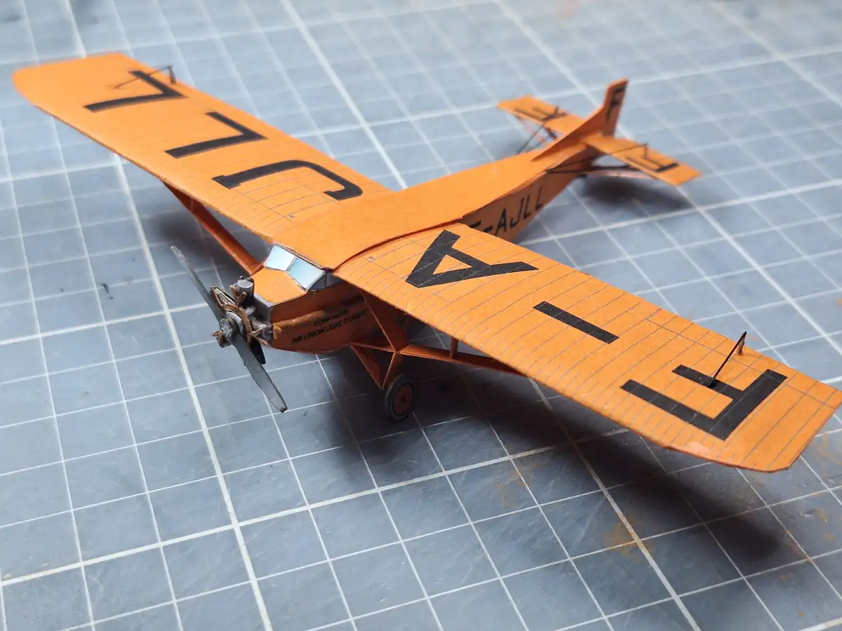 A handmade orange biplane model with black lettering on its wings and fuselage, including the text 'COMPAGNIE AIR UNION…