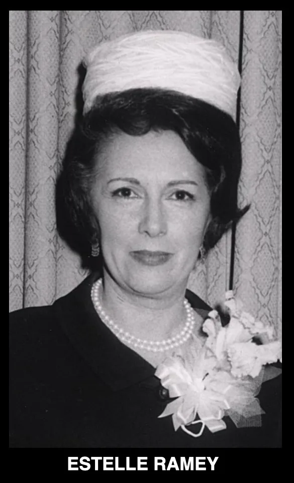 A black and white portrait of a woman with dark, styled hair, wearing a white pillbox-style hat, a pearl necklace, and a…
