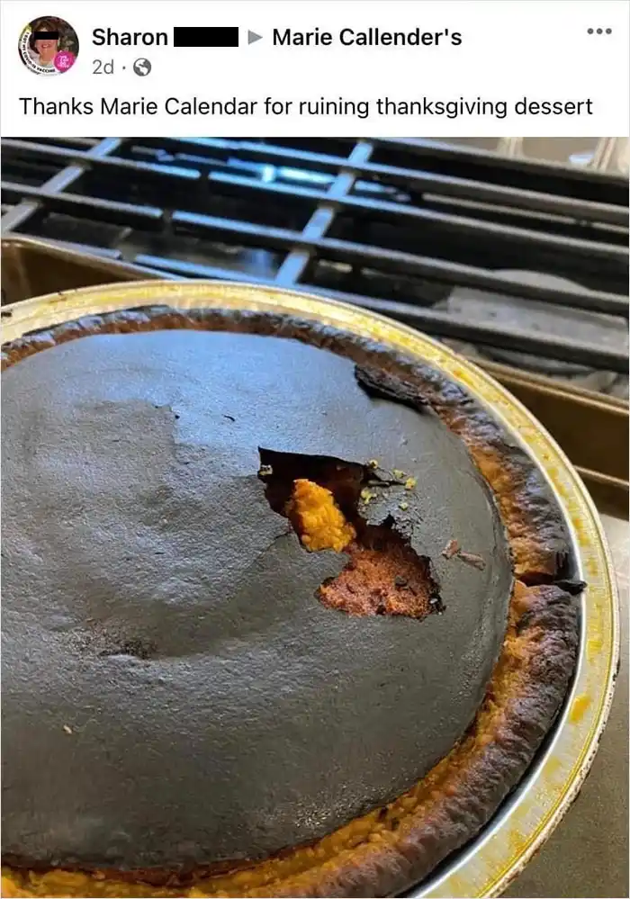 A close-up photo of a burnt Thanksgiving pie with a dark, charred top and a small hole revealing the orange filling…