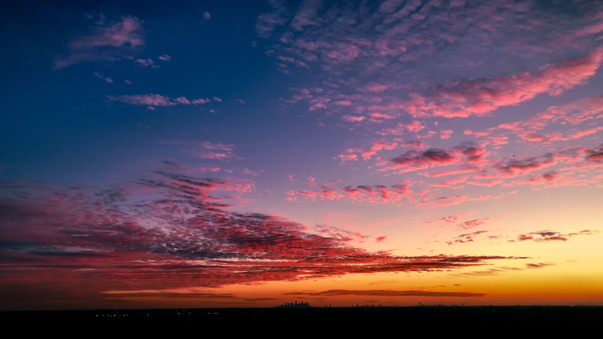 A breathtaking sunset or sunrise photo showing a sky transitioning from deep blue to vibrant pink, orange, and yellow hues…
