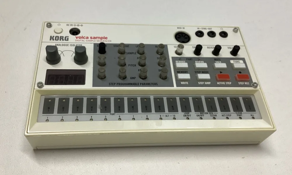 A beige Korg Volca Sample digital sample sequencer with knobs, buttons, and a small display, photographed on a plain white…