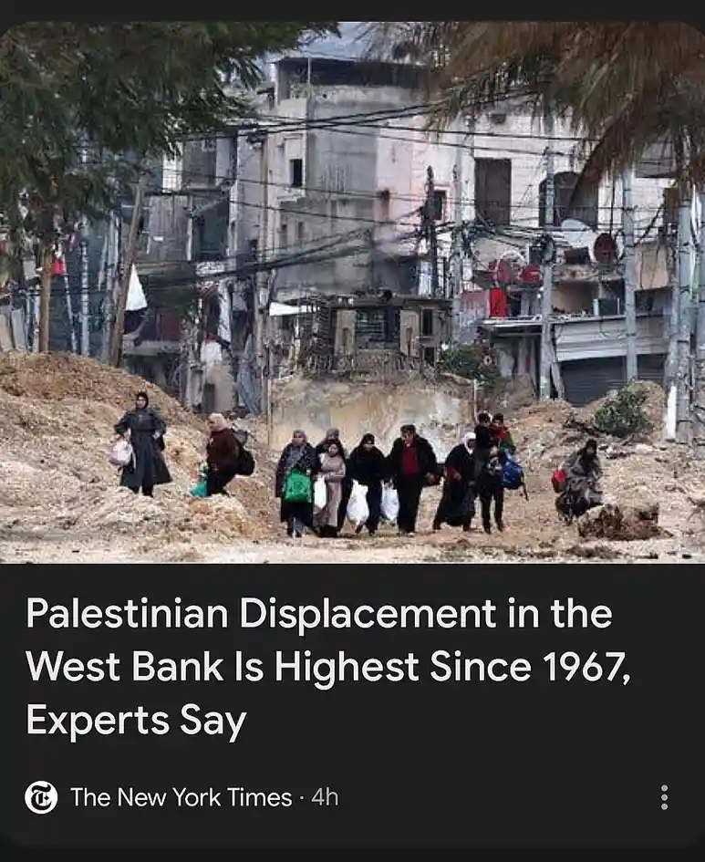A photo shows a group of people, mostly women and children, walking through a rubble-strewn area with damaged buildings in…