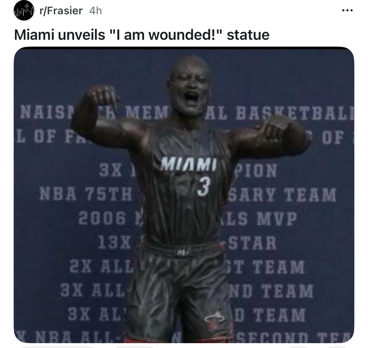A bronze statue of a basketball player in a Miami jersey with the number 3, arms raised in a triumphant pose, stands before…