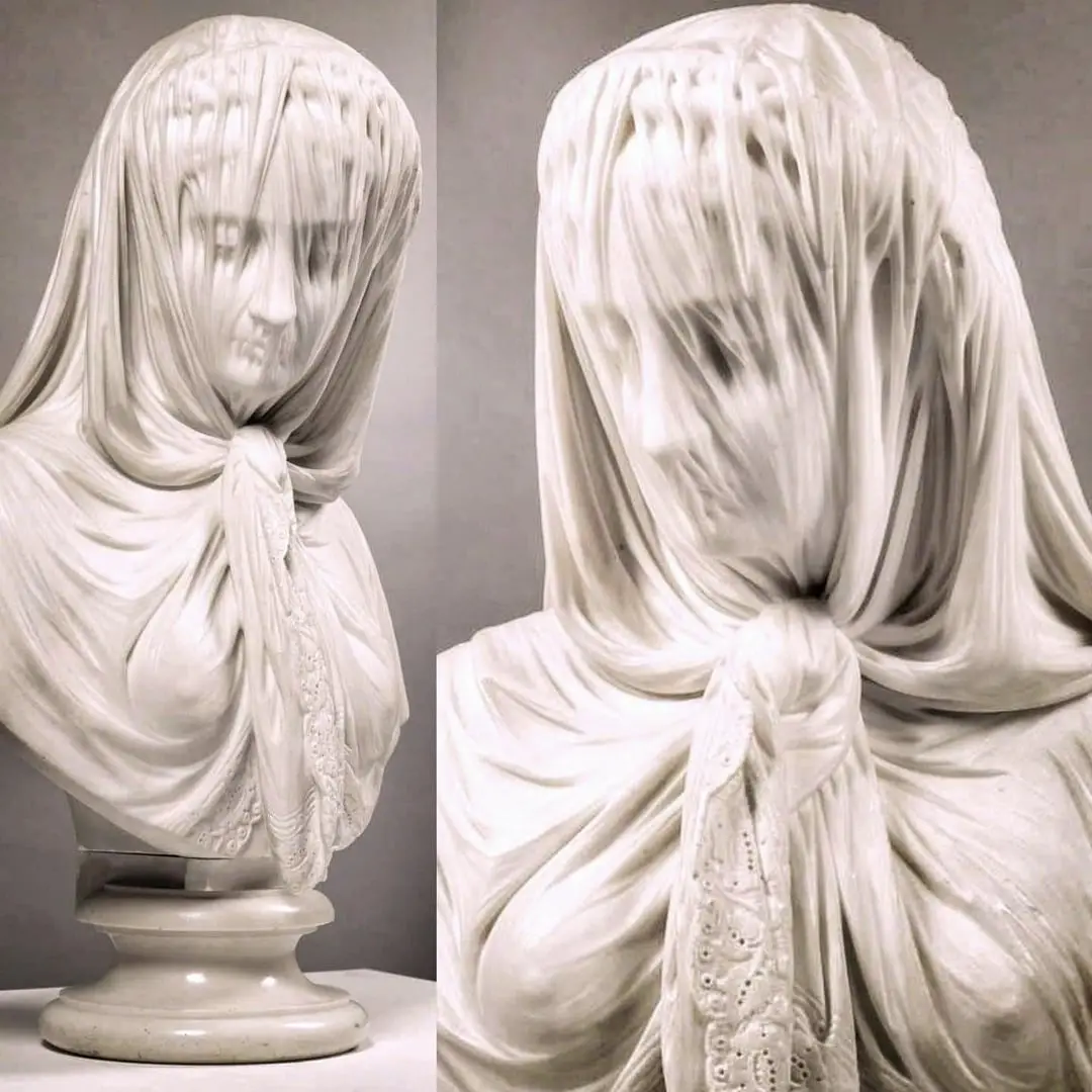 The image displays a marble bust of a woman with a heavy, intricately carved veil draped over her head and face, obscuring…
