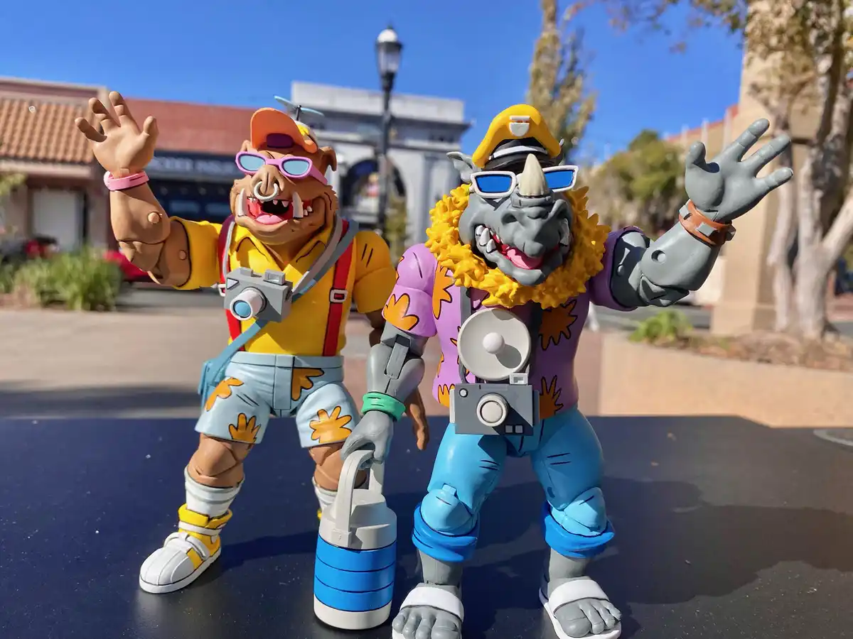 Two action figures of the characters from the movie 'The Croods' are posed outdoors, both wearing sunglasses and holding…
