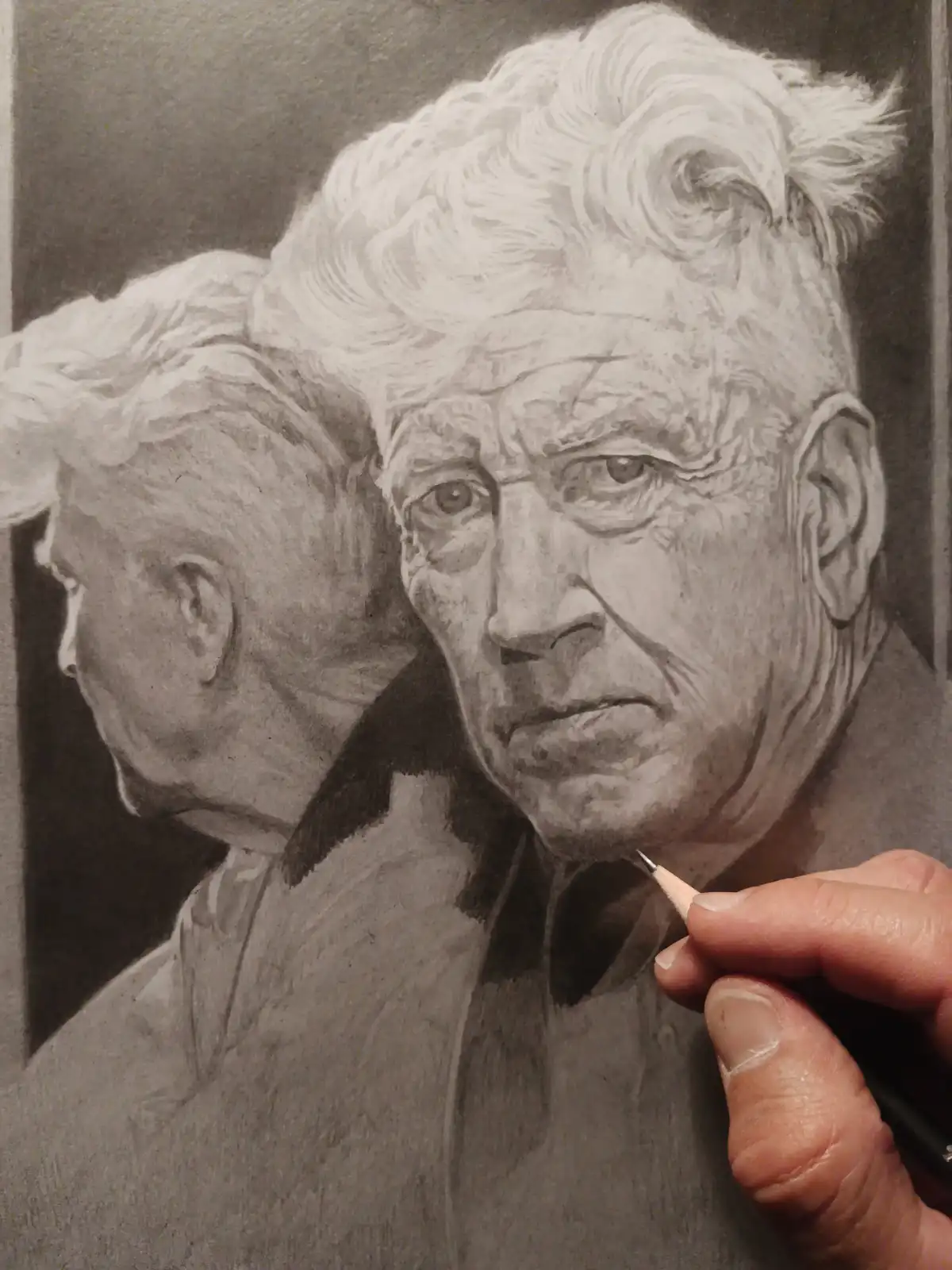 A detailed pencil sketch shows an elderly man with white hair and a stern expression, while a hand holding a pencil is…