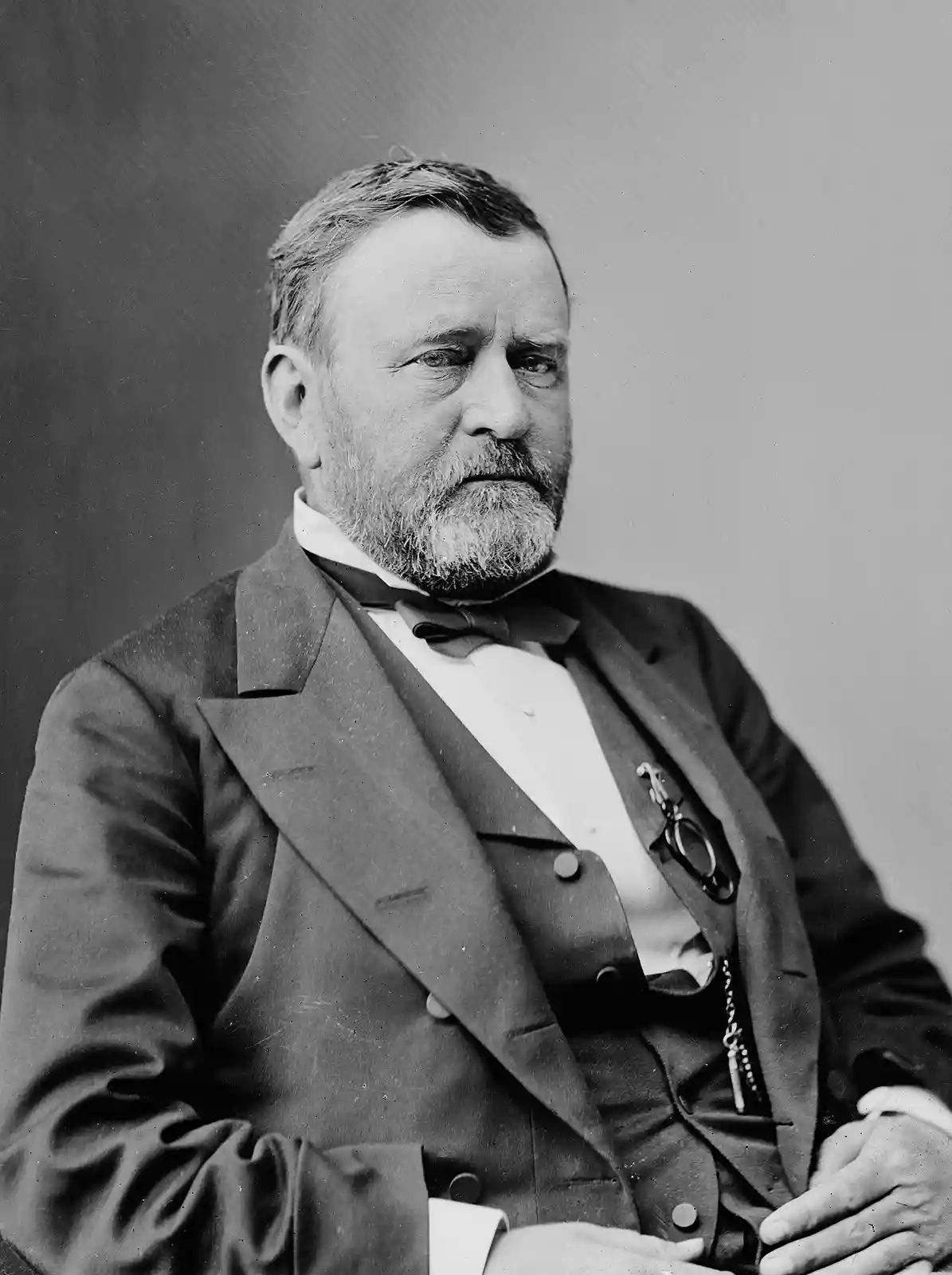 A black-and-white portrait of Ulysses S. Grant, the 18th U.S. president, wearing a formal suit with a bow tie and holding a…