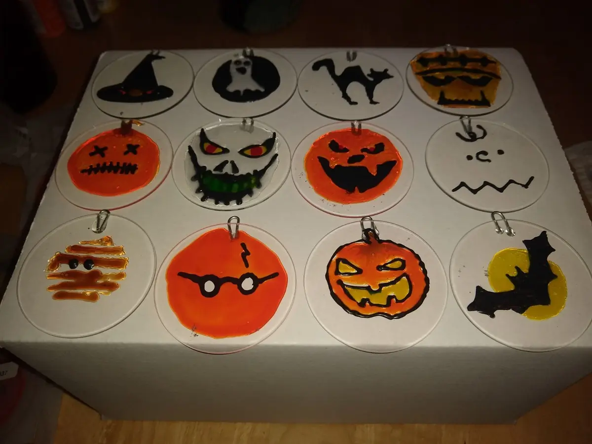 A collection of handmade Halloween decorations, each on a circular clear glass ornament, featuring various spooky designs…