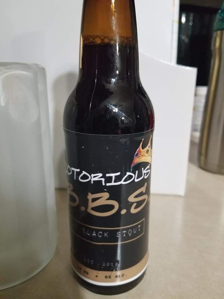 A close-up photo of a dark brown beer bottle with a black label that reads 'NOTORIOUS B.B.S. BLACK STOUT' and features a…