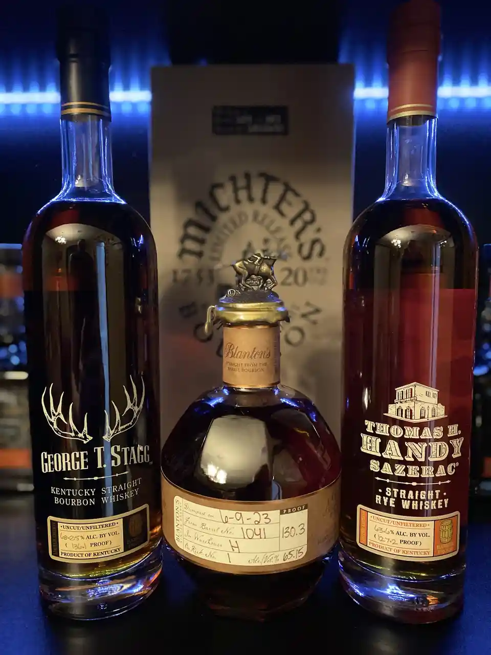 Three high-proof American whiskey bottles — George T. Stagg, Blanton's, and Thomas H. Handy Sazerac — are displayed…