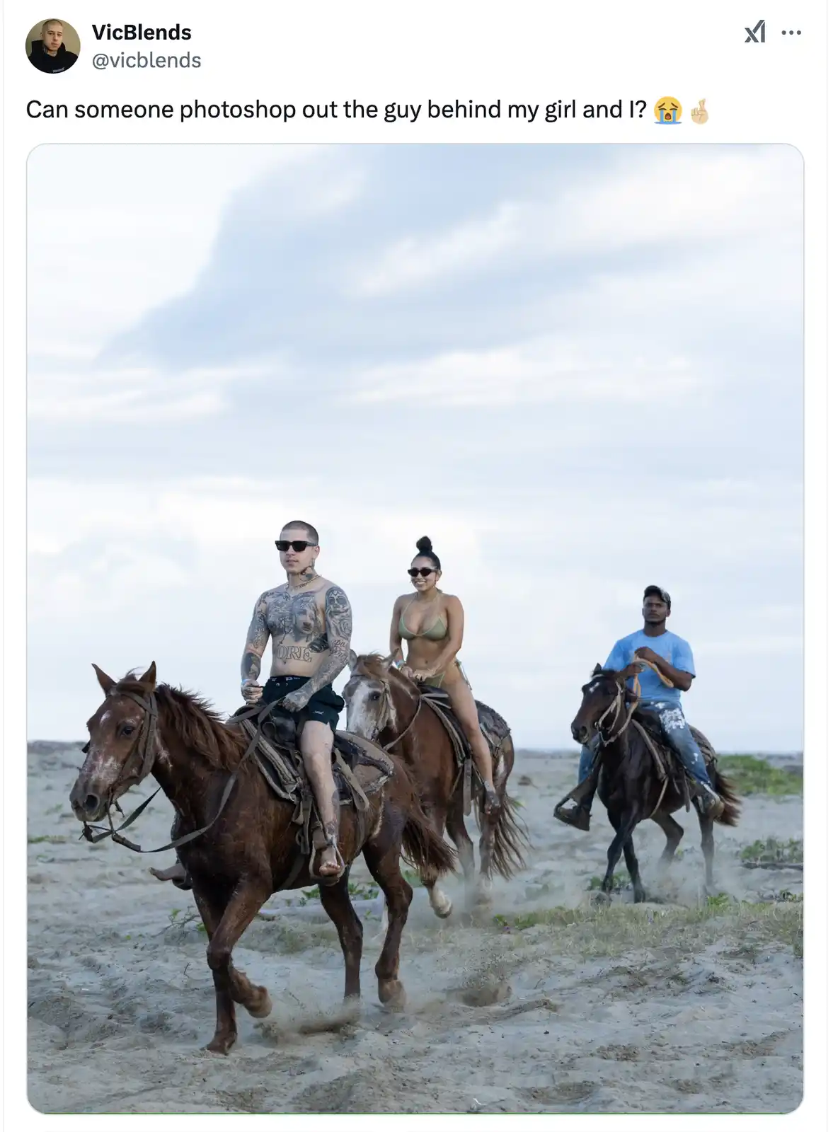 A man and woman ride horses on a sandy beach, with another man on a horse directly behind them. The man in the foreground…