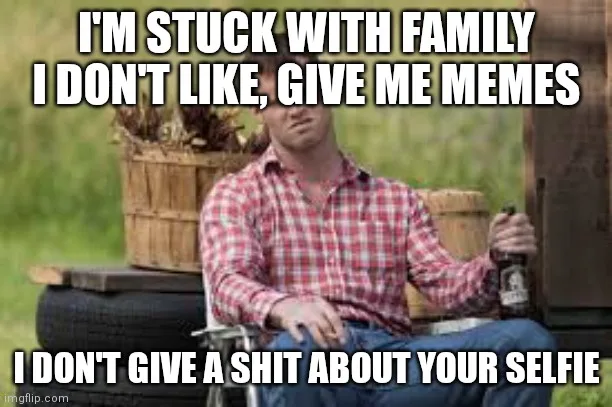 A man in a red and white checkered shirt sits in a folding chair outdoors, holding a beer bottle, looking bored and…