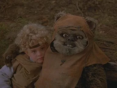 Six identical frames show a young child with curly blonde hair and a brown headband hugging a furry, brown-robed creature…