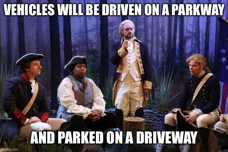 Four men dressed in colonial American military uniforms sit or stand in a forest setting. One man stands and gestures while…