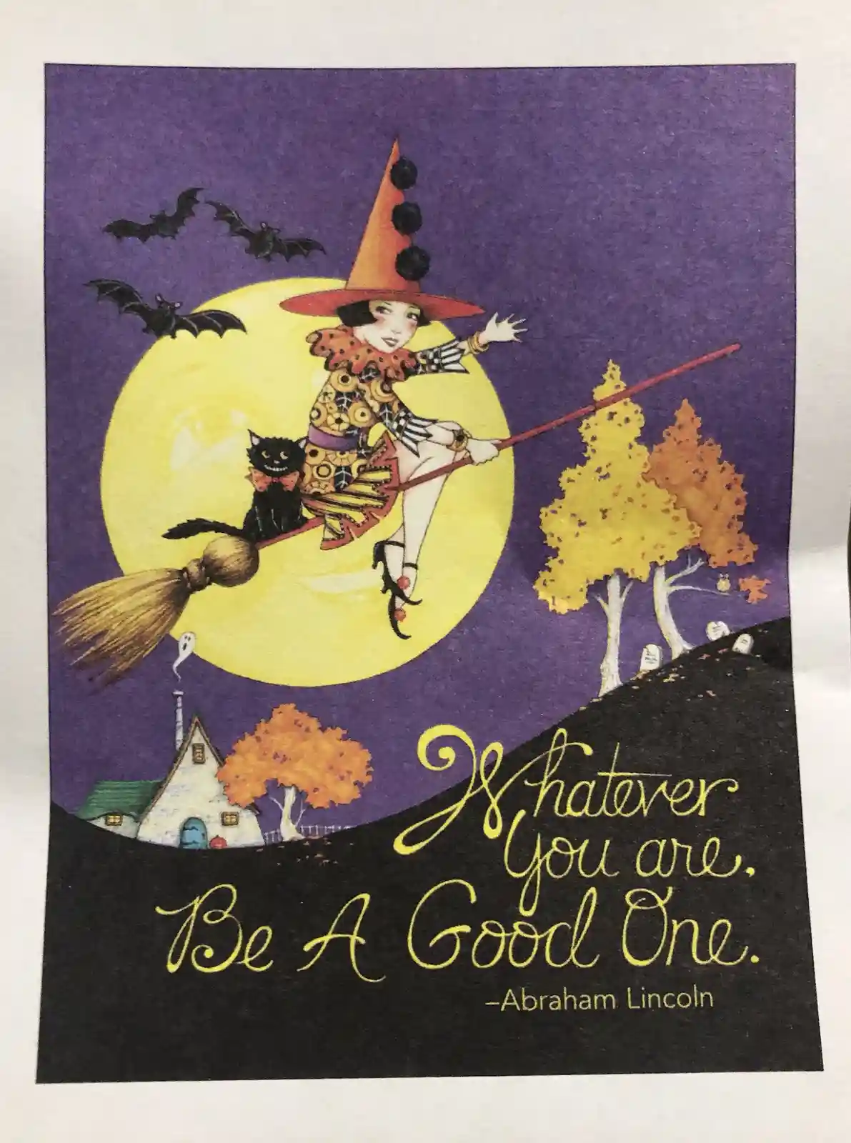 A whimsical Halloween illustration shows a witch in a tall orange hat with black pom-poms flying on a broomstick against a…