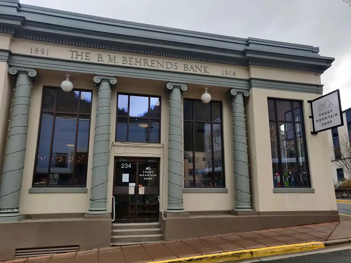 An old bank building with classical columns and engraved text reading 'THE B.M. BEHRENDS BANK 1891 1914' is now a retail…