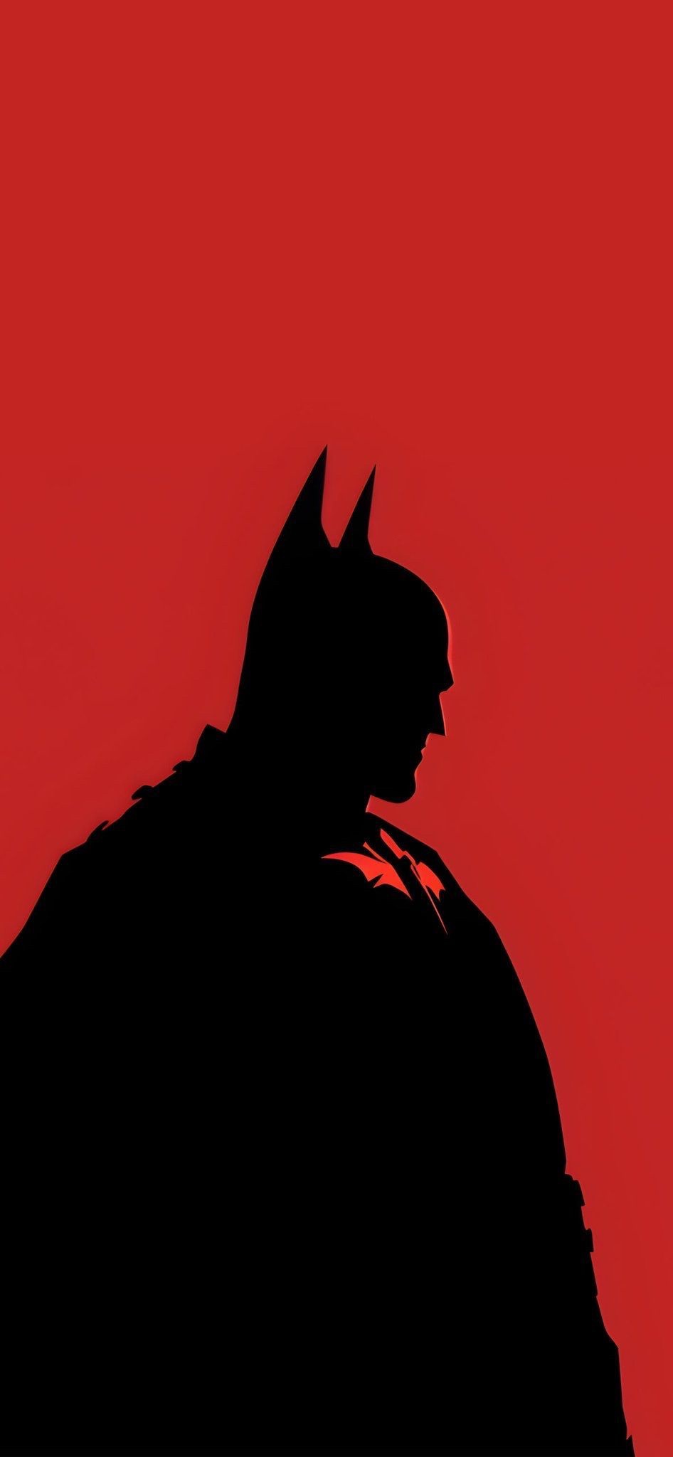 A stark black silhouette of Batman is shown in profile against a solid red background, with the iconic bat emblem visible on…